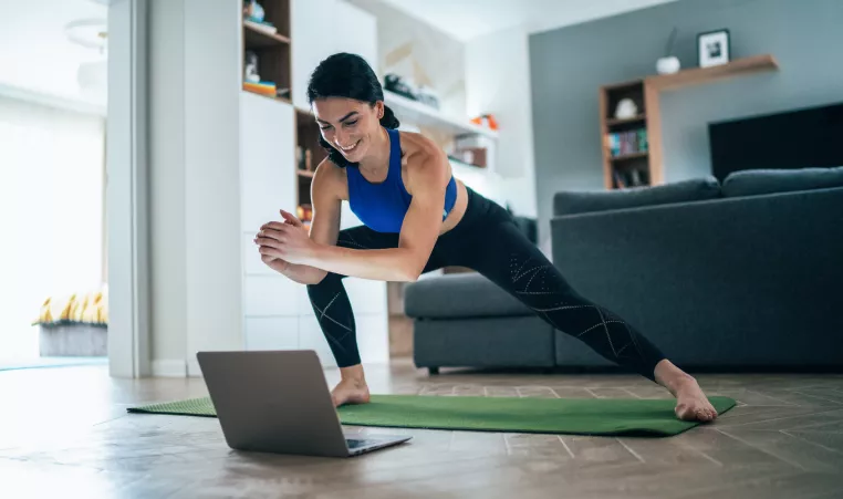 Woman stretching at home with laptop