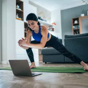 Woman stretching at home with laptop